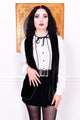 Woman wearing a black and white outfit with a belt, standing against a plain background.