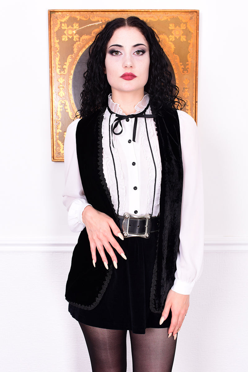 Woman wearing a black and white outfit with a belt, standing against a plain background.