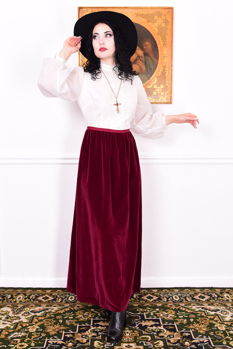 Woman wearing a vintage 1970s maxi dress in white and burgundy velvet by Angela Gore.