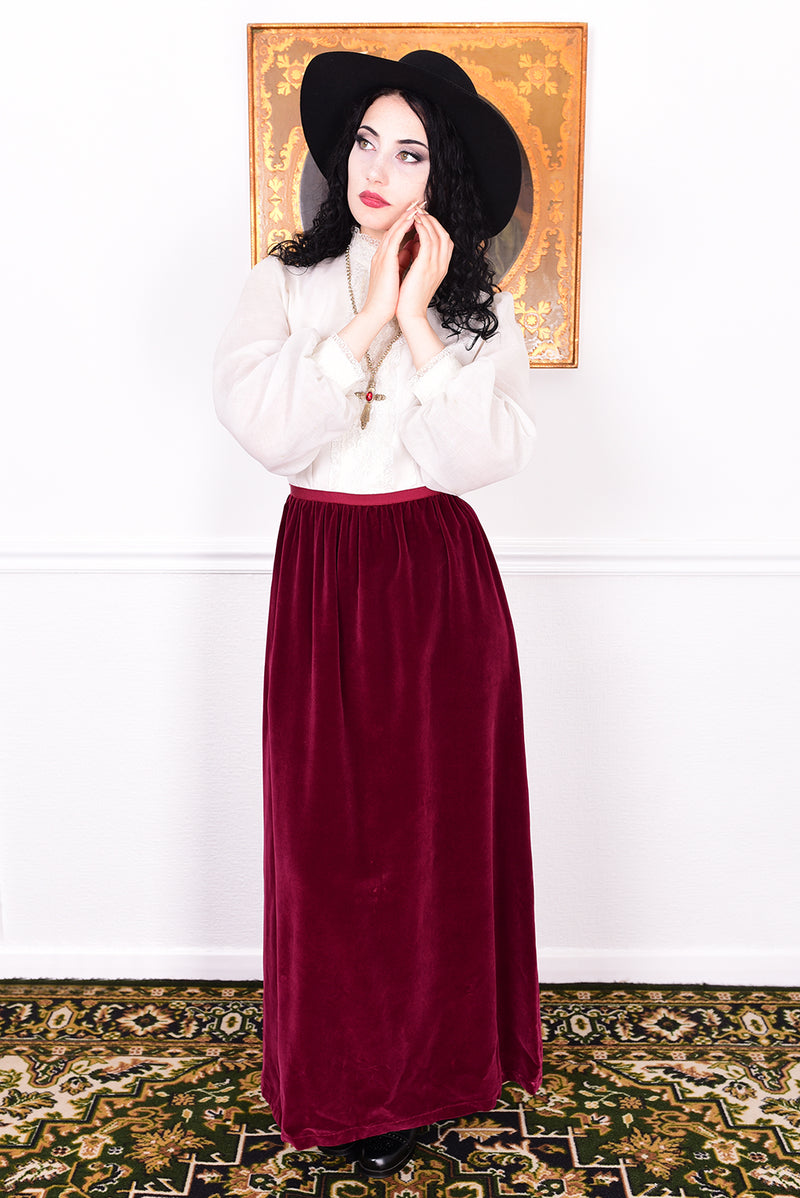 Woman wearing a vintage 1970s maxi dress in white and burgundy velvet by Angela Gore.