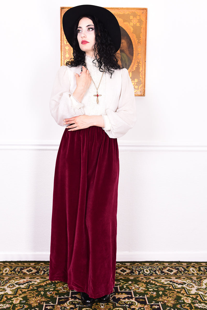 Woman wearing a vintage 1970s maxi dress in white and burgundy velvet by Angela Gore.