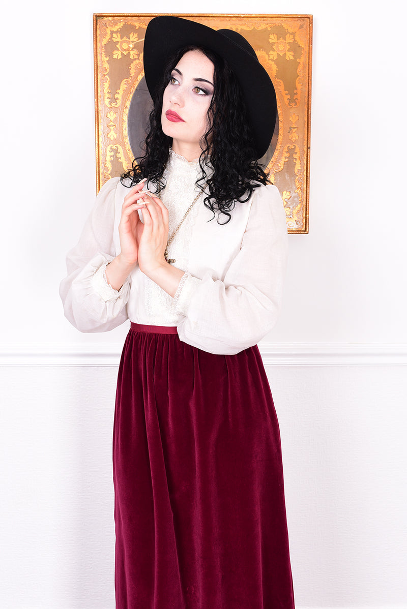 Woman wearing a vintage 1970s maxi dress in white and burgundy velvet by Angela Gore.