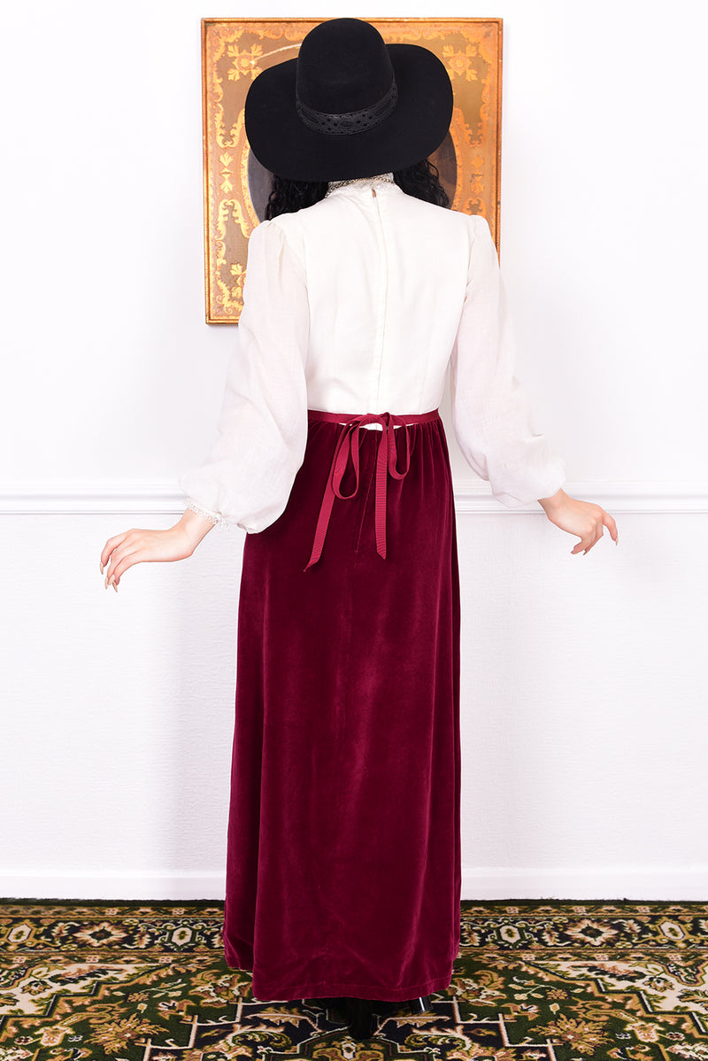 Woman wearing a vintage 1970s maxi dress in white and burgundy velvet by Angela Gore.