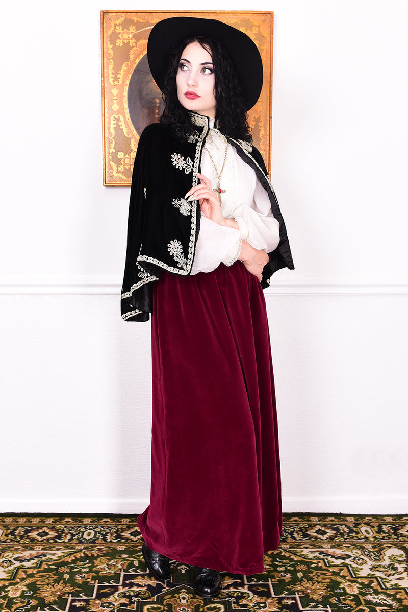 Woman wearing an antique early 1900s black embroidered cape over a dress.