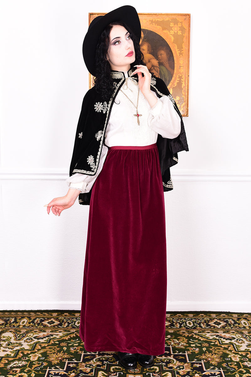 Woman wearing an antique early 1900s black embroidered cape over a dress.