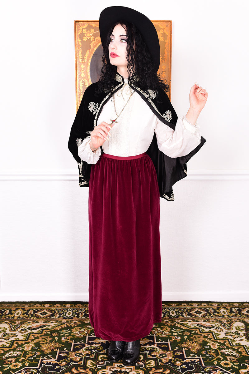 Woman wearing an antique early 1900s black embroidered cape over a dress.