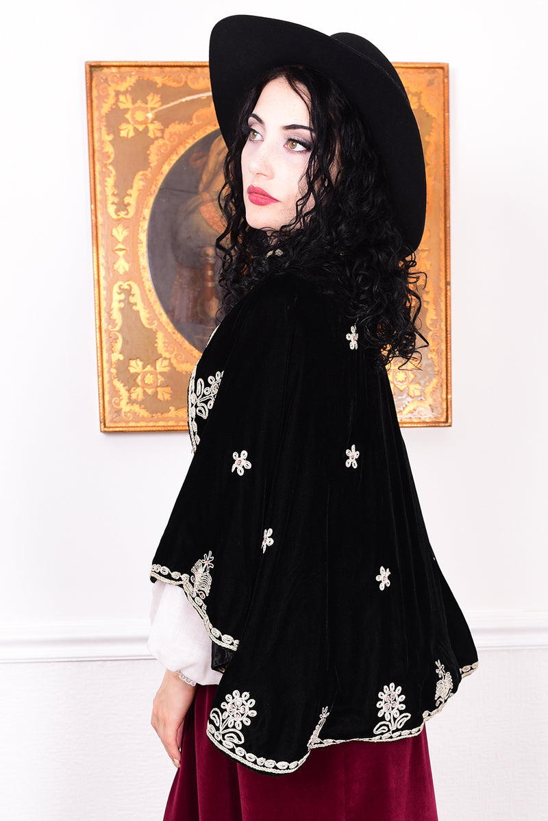 Woman wearing an antique early 1900s black embroidered cape over a dress.