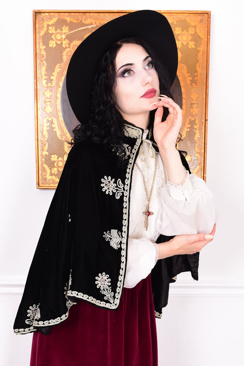 Woman wearing an antique early 1900s black embroidered cape over a dress.