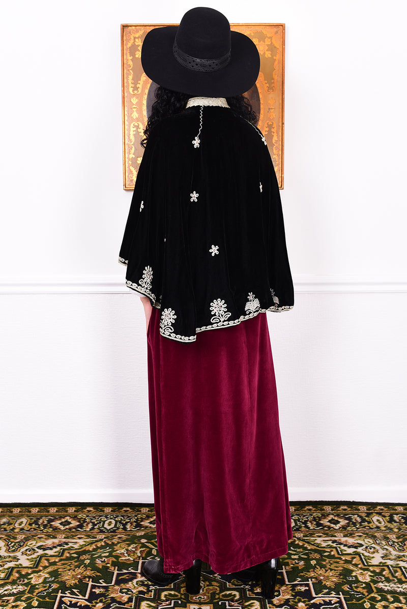 Woman wearing an antique early 1900s black embroidered cape over a dress.