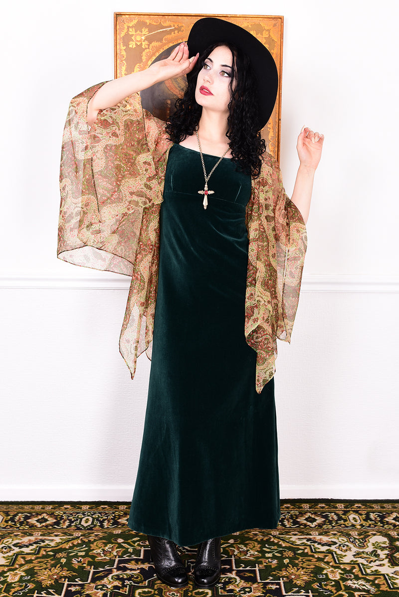 Woman in a vintage 1970s emerald green velvet dress with floaty floral print sleeves by Quad.