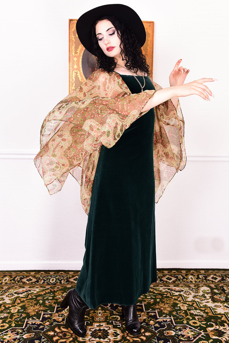 Woman in a vintage 1970s emerald green velvet dress with floaty floral print sleeves by Quad.