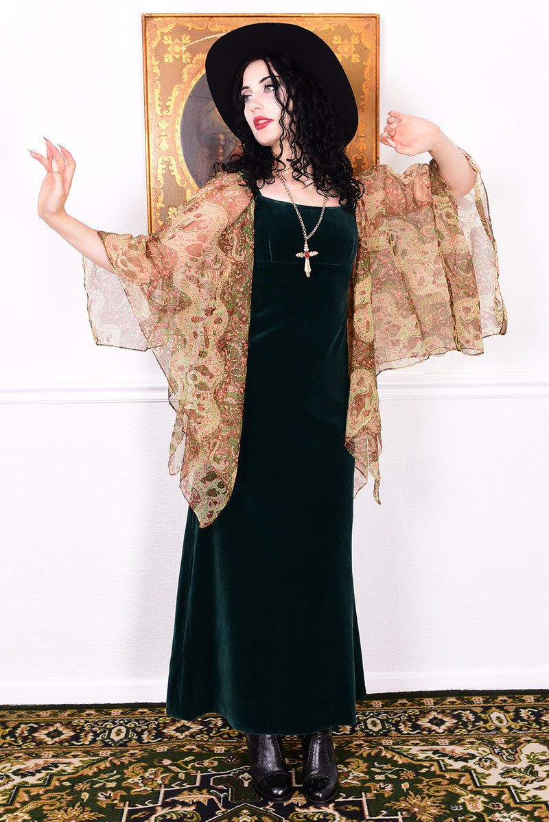 Woman in a vintage 1970s emerald green velvet dress with floaty floral print sleeves by Quad.
