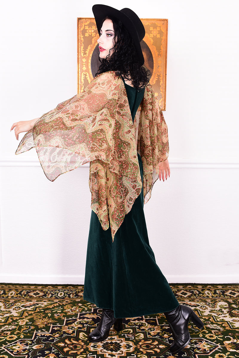 Woman in a vintage 1970s emerald green velvet dress with floaty floral print sleeves by Quad.