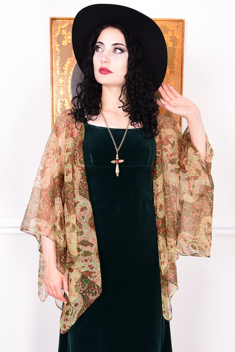 Woman in a vintage 1970s emerald green velvet dress with floaty floral print sleeves by Quad.