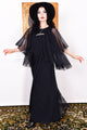 Woman wearing a black vintage 1970s floaty dress with sheer sleeves.