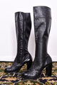 Pair of vintage 1970s black knee-high boots on a patterned rug.