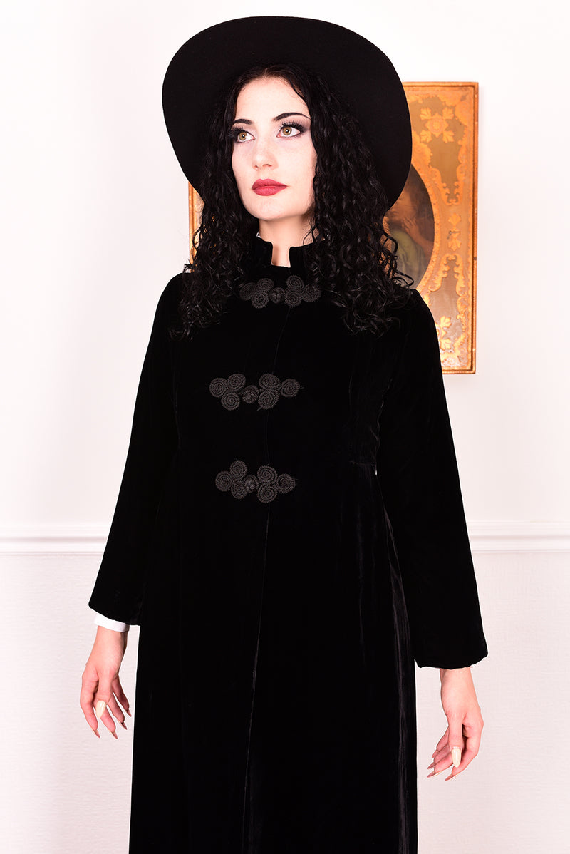 Woman wearing a vintage 1960s long black velvet coat and hat.