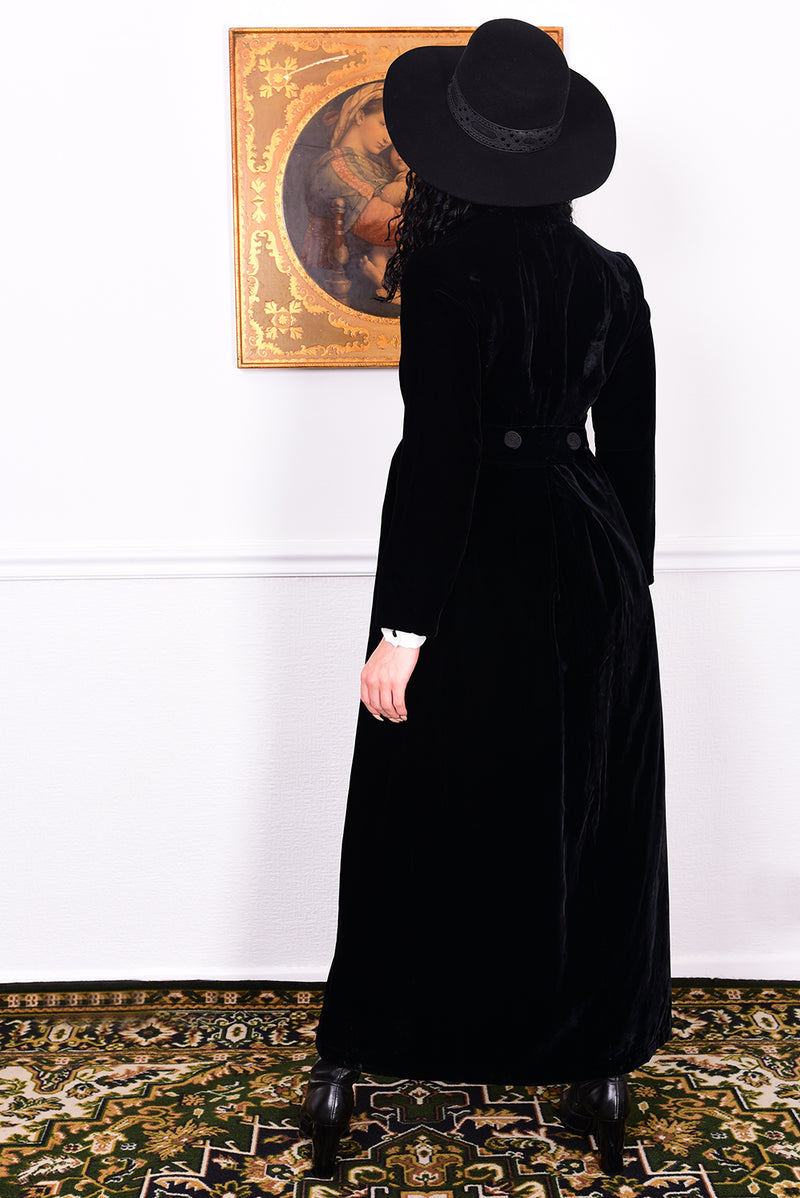Woman wearing a vintage 1960s long black velvet coat and hat.
