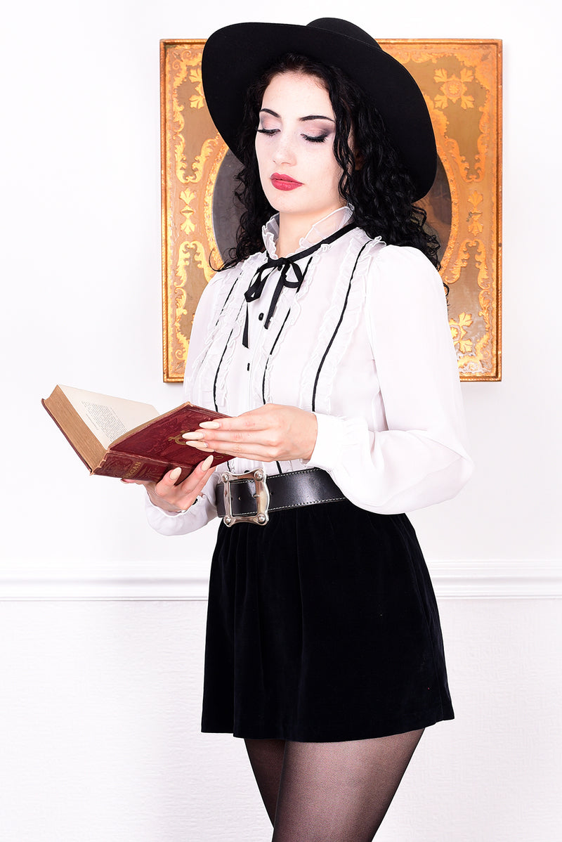Woman in vintage attire holding a book against a white background