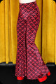 A pair of red logo print velvet bell bottom trousers by Scorpio Rising