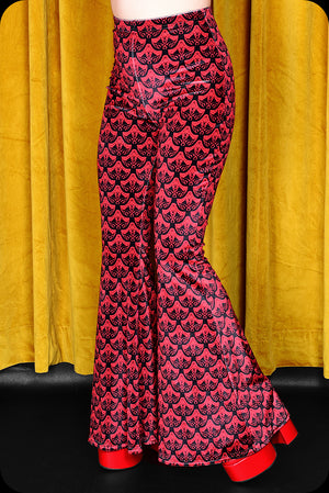 A pair of red logo print velvet bell bottom trousers by Scorpio Rising
