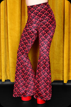 A pair of red logo print velvet bell bottom trousers by Scorpio Rising