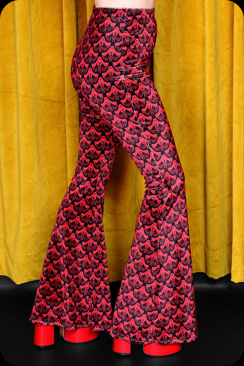 A pair of red logo print velvet bell bottom trousers by Scorpio Rising