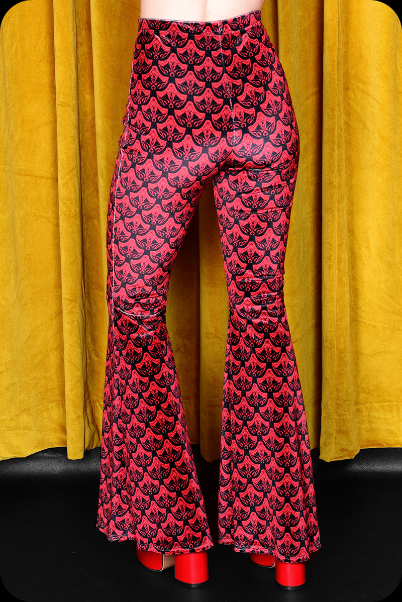 A pair of red logo print velvet bell bottom trousers by Scorpio Rising